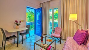 A hotel room with a dining area, a bed, a chair, a table with a bottle and glasses, and a view of greenery outside. - Cozy Apartment Amoudara Heraklion Crera-5 (Malevizi)