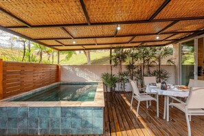A covered outdoor area with a pool, wooden deck, and seating. - Fazenda Realeza (Pedra Bela)