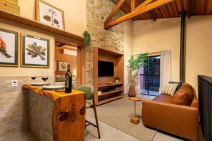 A cozy living room with a stone wall, wooden furniture, a TV, and a sofa. - Fazenda Realeza (Pedra Bela)