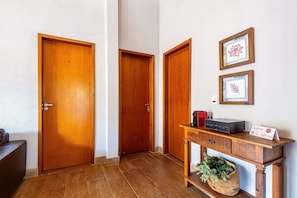 A hallway with wooden doors, a desk with a printer, and framed artwork on the wall. - Fazenda Realeza (Pedra Bela)