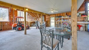 Un espace intérieur spacieux avec une table et des chaises en verre, des poutres en bois et un ventilateur de plafond.
