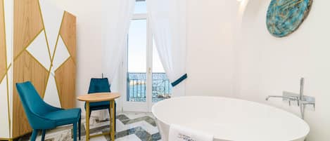 Un baño moderno con una bañera independiente, una silla azul y una mesita.