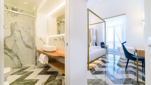 Un baño moderno con ducha de vidrio, suelo de mármol y tocador de madera.
