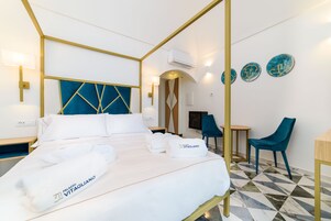Una habitación de hotel con cama, dos sillas, un escritorio y platos decorativos en la pared.
