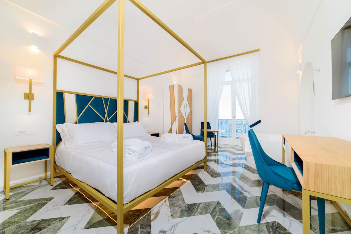 A modern hotel room with a four-poster bed, a desk, and a chair.