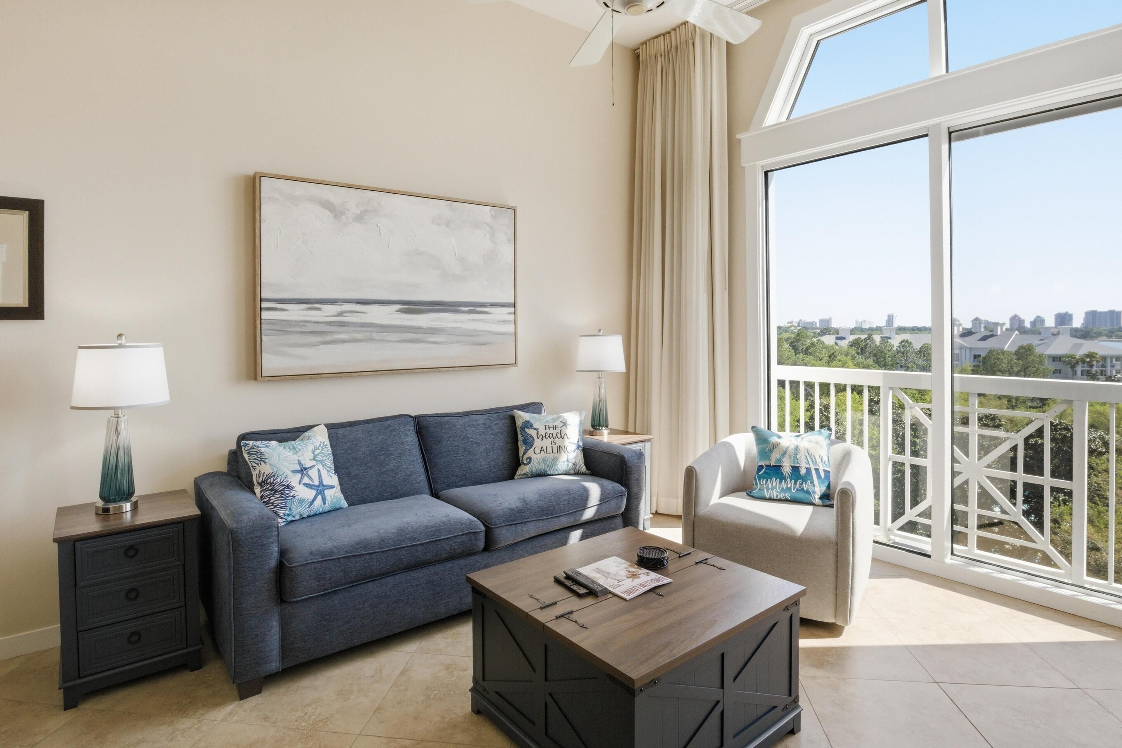 A modern living room with a sofa, coffee table, and a view of the city through large windows.