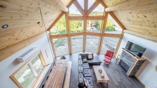 Ein gemütliches Blockhaus-Interieur mit großem Fenster, einer Couch, einem Fernseher und einem Kamin.