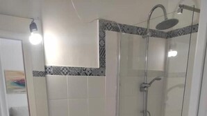 A modern bathroom with a toilet, sink, and glass-enclosed shower. - Ático con Terraza en los Remedios (Sevilla)