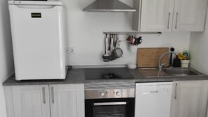 A compact kitchen with a refrigerator, microwave, stove, oven, and dishwasher. - Ático con Terraza en los Remedios (Sevilla)