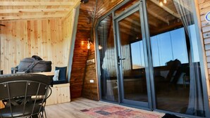 A wooden interior with a dining area, a sliding glass door leading outside, and a visible outdoor view. - İnce Bungalov (Sapanca)