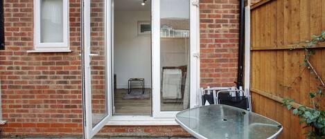 A brick house with a glass door leading to a room. A table is outside the door.