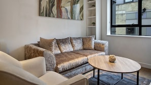 Ein modernes Wohnzimmer mit einer Couch, einem Couchtisch und einem großen abstrakten Gemälde an der Wand.