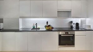 Eine moderne Küche mit weißen Schränken, einer schwarzen Arbeitsplatte, einem Bosch-Ofen und einer Kaffeemaschine.
