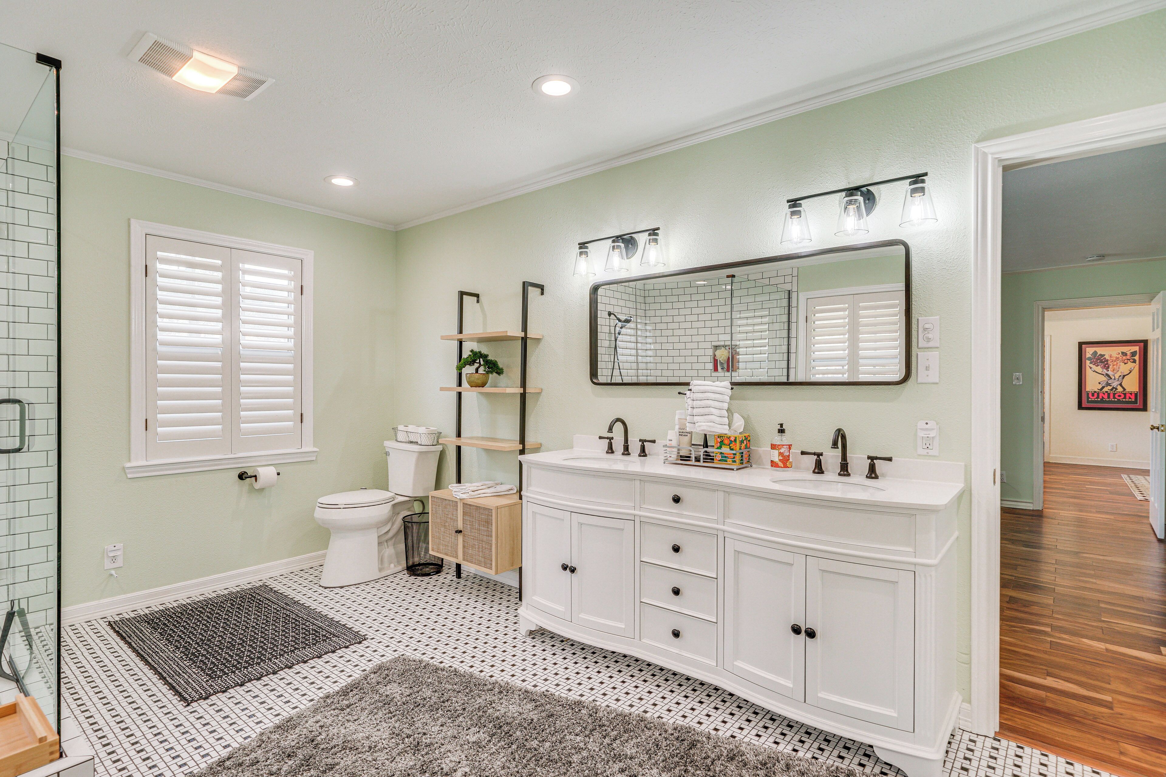 A bathroom with a white vanity, a large mirror, and a toilet.