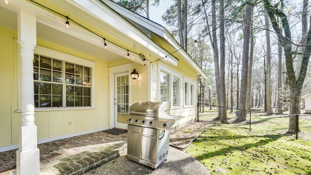 Et hus med en overdækket veranda, grill og et skovområde i baggrunden.