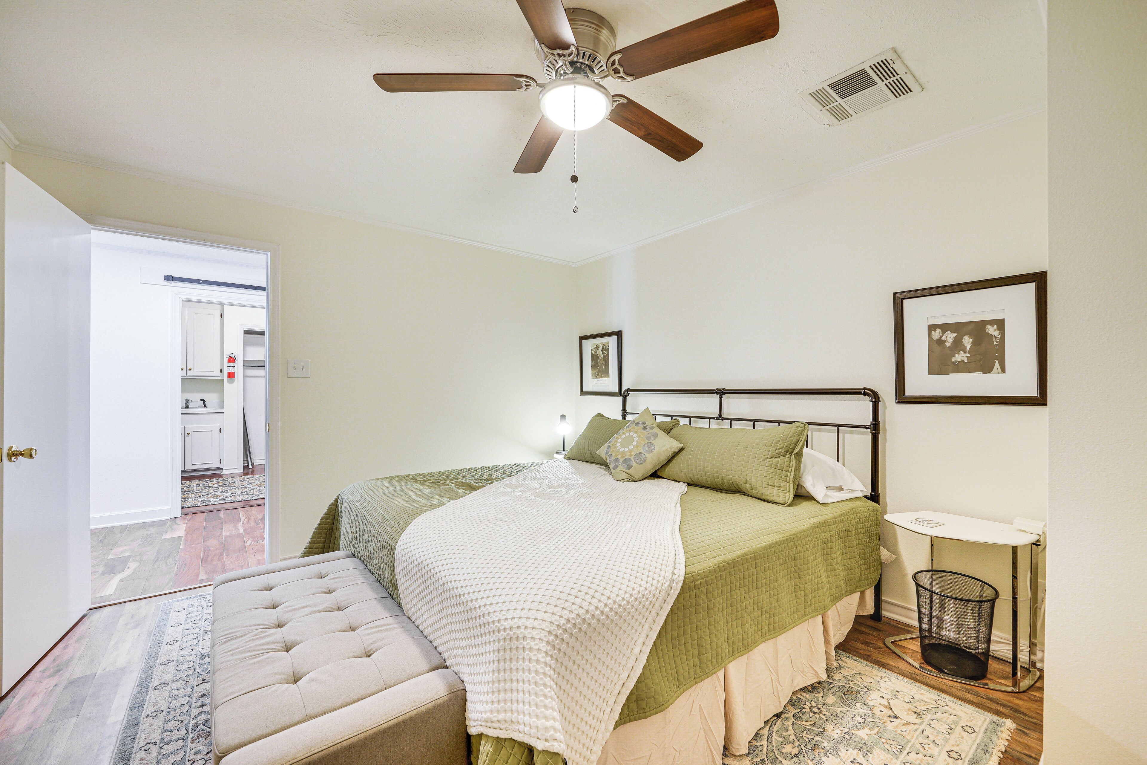 A bedroom with a bed, a ceiling fan, a bedside table, and a window.