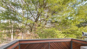 A wooden deck with a metal railing, surrounded by trees. - Community Beach Access: Lake Harmony Townhome (Lake Harmony)