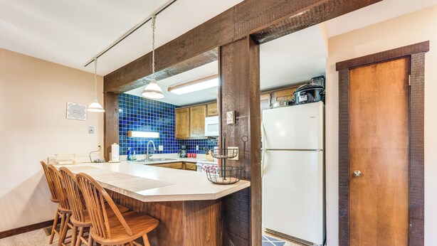 A kitchen with a wooden island, bar stools, a refrigerator, and a blue-tiled backsplash. - Community Beach Access: Lake Harmony Townhome (Lake Harmony)