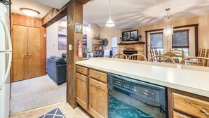 A kitchen with wooden cabinets, a dishwasher, and a dining area with chairs. - Community Beach Access: Lake Harmony Townhome (Lake Harmony)