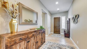 A hallway with a wooden cabinet, a mirror, and a decorative vase. - Home w/ Hot Tub & Outdoor Space in Queen Creek! (Queen Creek)