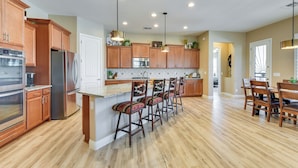 A modern kitchen with wooden cabinets, stainless steel appliances, and a central island with bar stools. - Home w/ Hot Tub & Outdoor Space in Queen Creek! (Queen Creek)