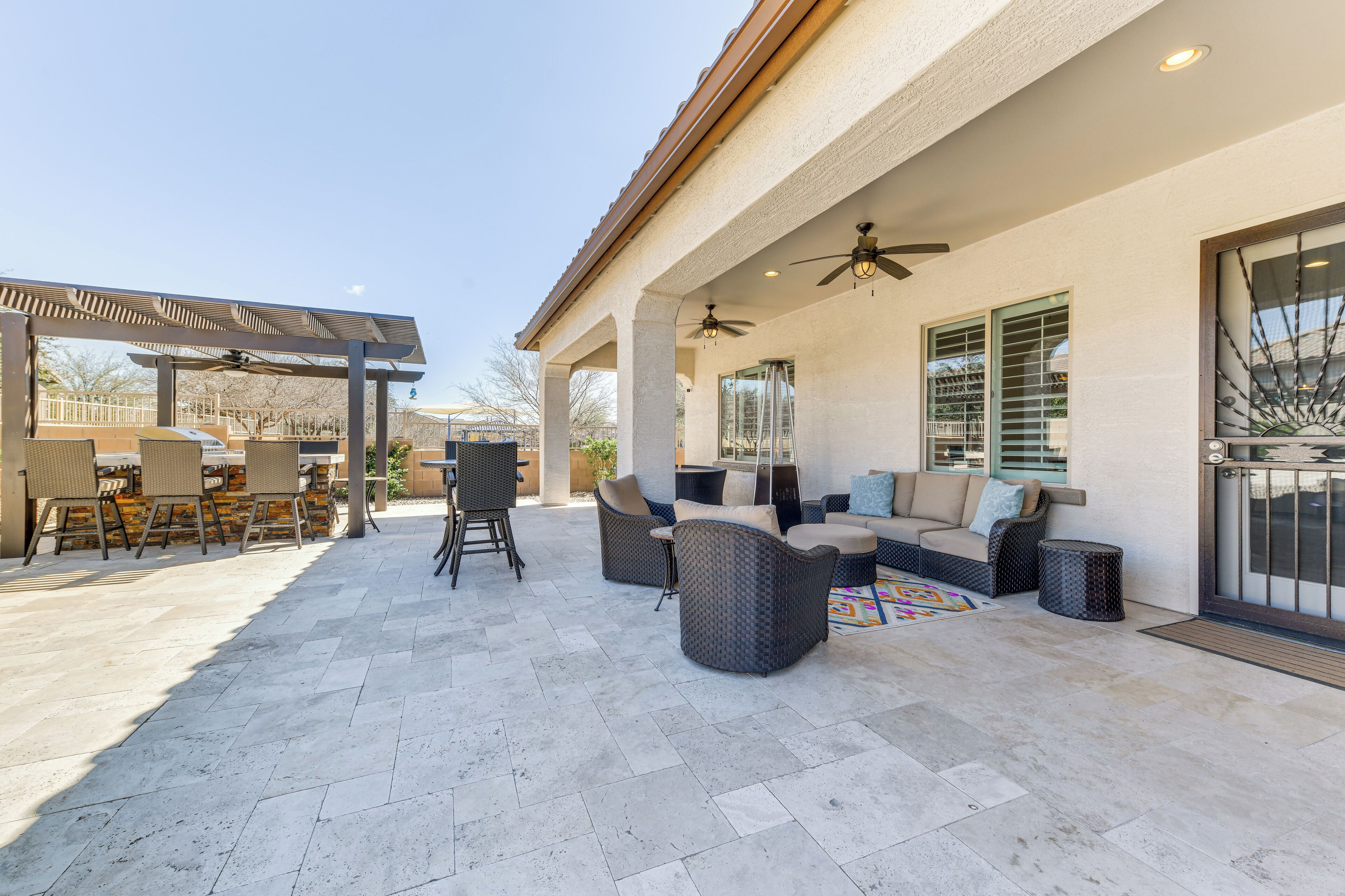 Een terras buiten met zitplaatsen, een pergola en een overdeeld gedeelte.