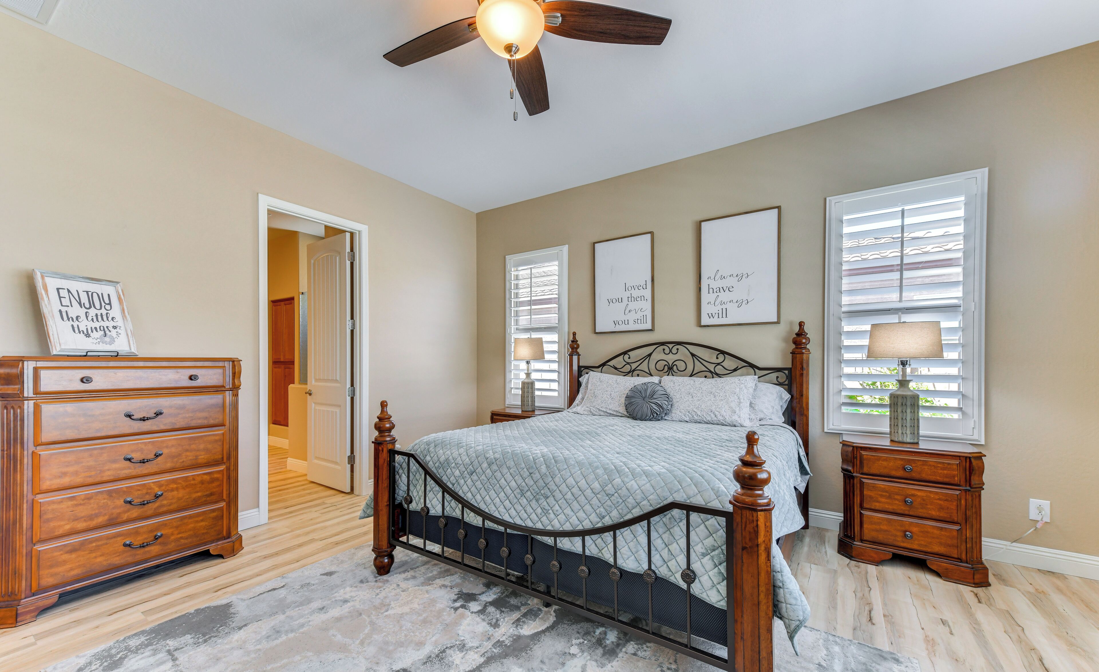 A bedroom with a bed, dresser, nightstands, and a ceiling fan.
