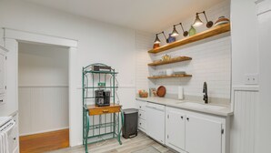 Eine Küche mit weißen Schränken, einer Holz Arbeitsplatte und einer Kaffeestation.