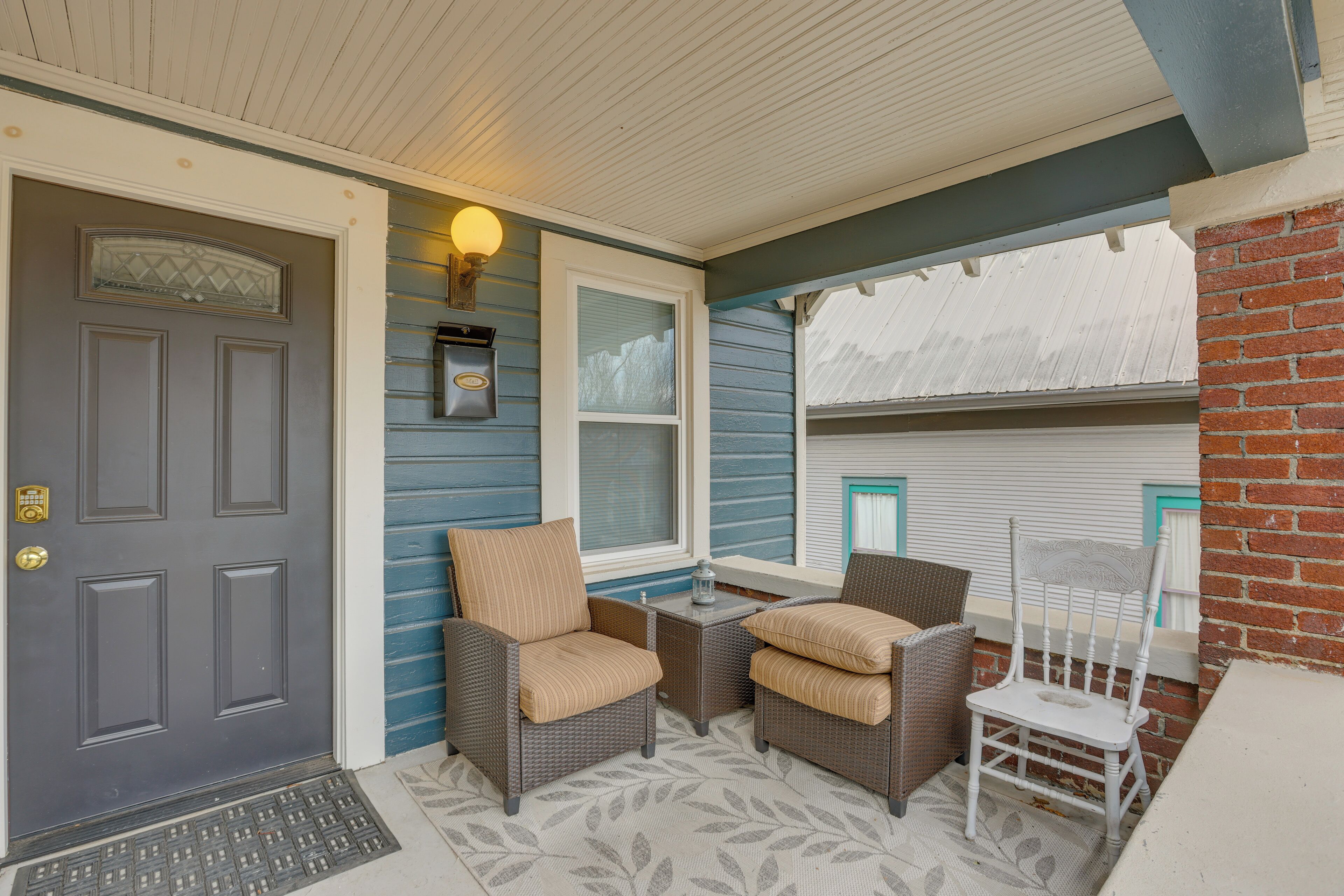 A porch with two wicker chairs, a small table, and a door.
