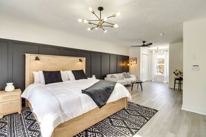 A bedroom with a large bed, a modern chandelier, and a view of the living area. - 5 Mi to Lake Naomi: Home w/ Hot Tub & Fire Pit (Long Pond)