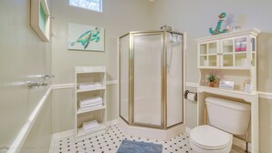 A bathroom with a shower, toilet, and shelves with towels. - Inglis Studio Home w/ Covered Patio & Grill! (Inglis)