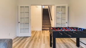 A room with a wooden floor, a foosball table, and a staircase leading to another room. - Quiet Avon Home - Near Indianapolis Speedway! (Avon)