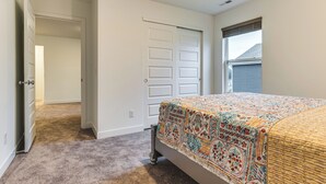 A bedroom with a bed, a door, a window, and a carpeted floor. - Quiet Avon Home - Near Indianapolis Speedway! (Avon)