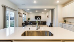 Een moderne keuken met een groot kookeiland, een RVS-spoelbak en inbouwspots.