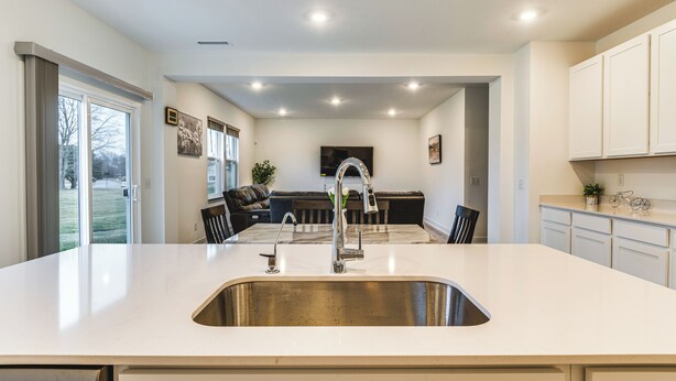 A modern kitchen with a large island, stainless steel sink, and overhead lighting. - Quiet Avon Home - Near Indianapolis Speedway! (Avon)