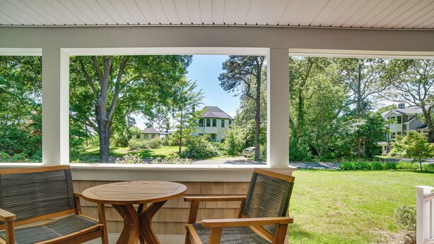 Une terrasse couverte, dotée de mobilier en bois, qui offre une vue sur un quartier résidentiel.