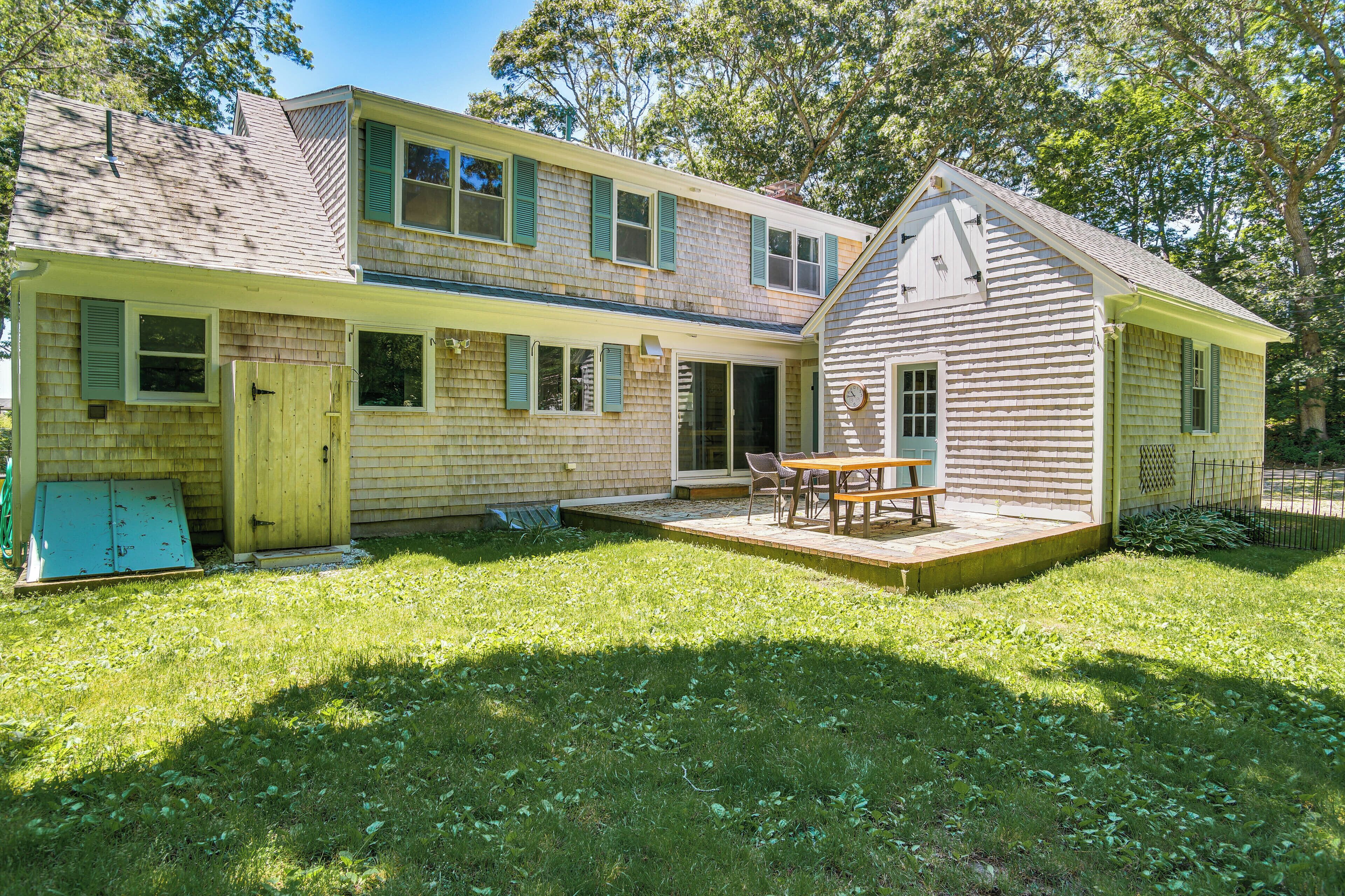 A two-story house with a covered patio and a small shed.