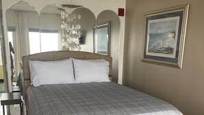 A bedroom with a large bed, a bedside table, a mirror, and a framed picture on the wall. - SUNRISE IN BED~BREATHTAKING OCEAN VIEWS~COUPLES RETREAT! (Hampton)