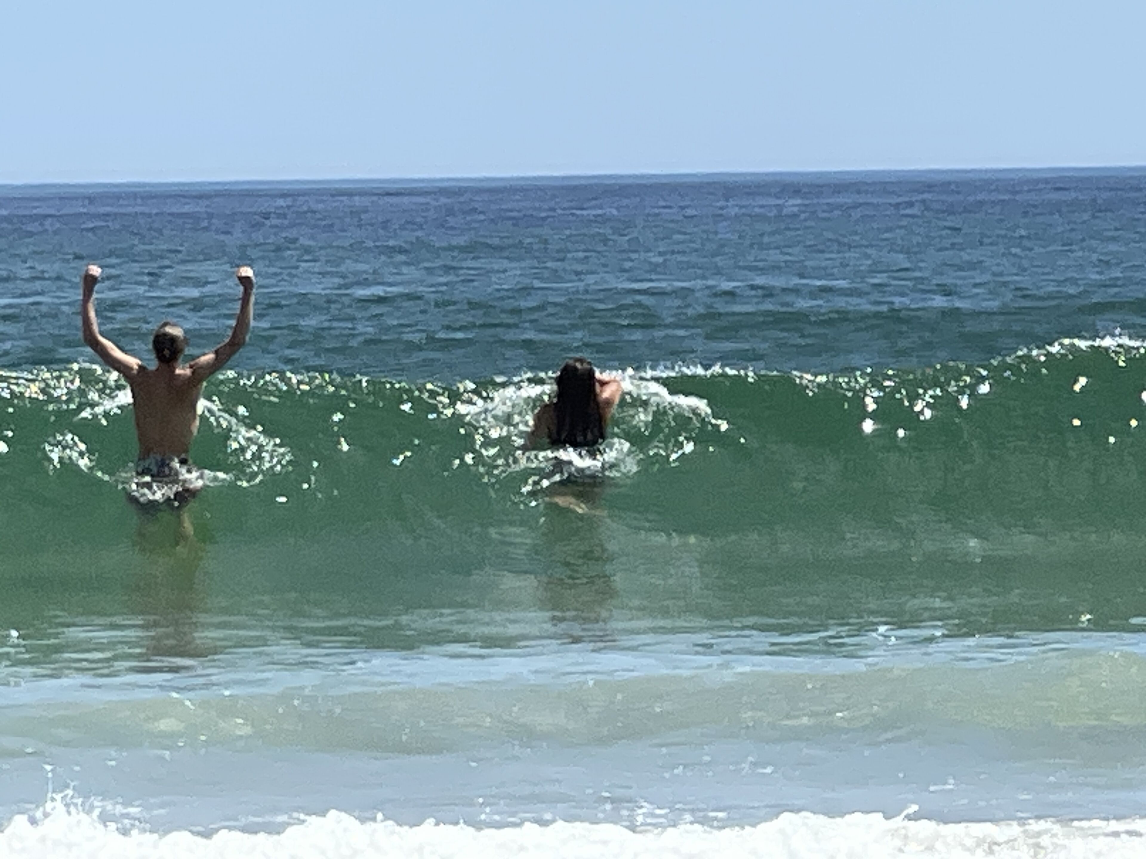 Two people surfing on a wave in the ocean.