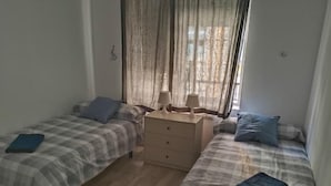 Een slaapkamer met twee eenpersoonsbedden, een nachtkastje en een dressoir.