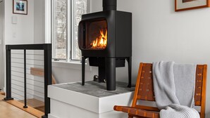 A modern living room with a black wood-burning stove, a white sofa, and a framed picture on the wall. - 22 Village Run 3 Bedroom Condo by RedAwning (Warren)