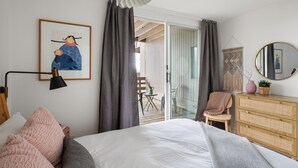 A bedroom with a bed, a dresser, a chair, a framed picture, and a balcony with a view. - 22 Village Run 3 Bedroom Condo by RedAwning (Warren)