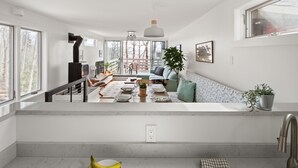 A modern kitchen with a central island, a dining area with a sofa, and a view of the outdoors. - 22 Village Run 3 Bedroom Condo by RedAwning (Warren)