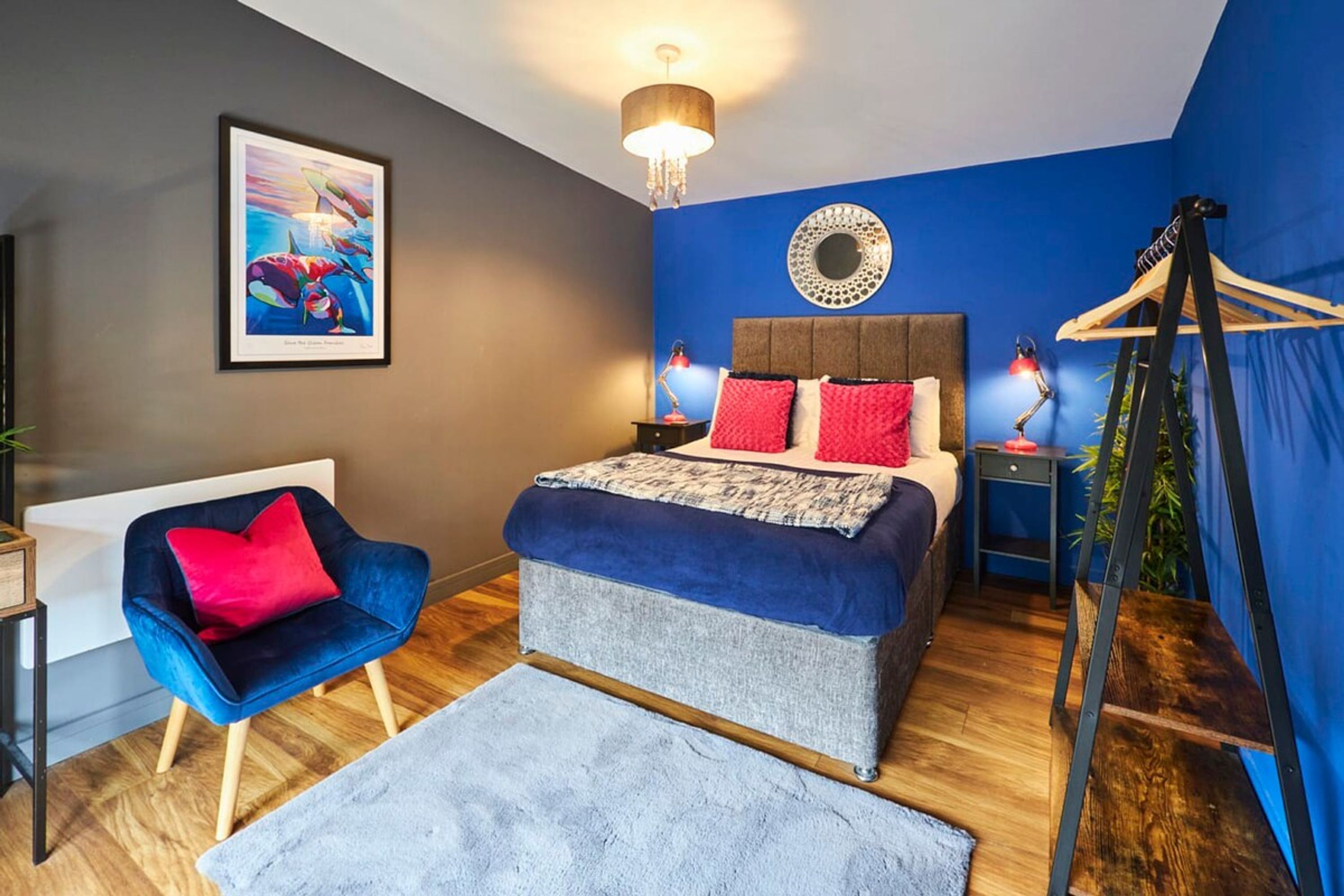 Un dormitorio moderno con cama, una silla, un escritorio y un sillón colgante.