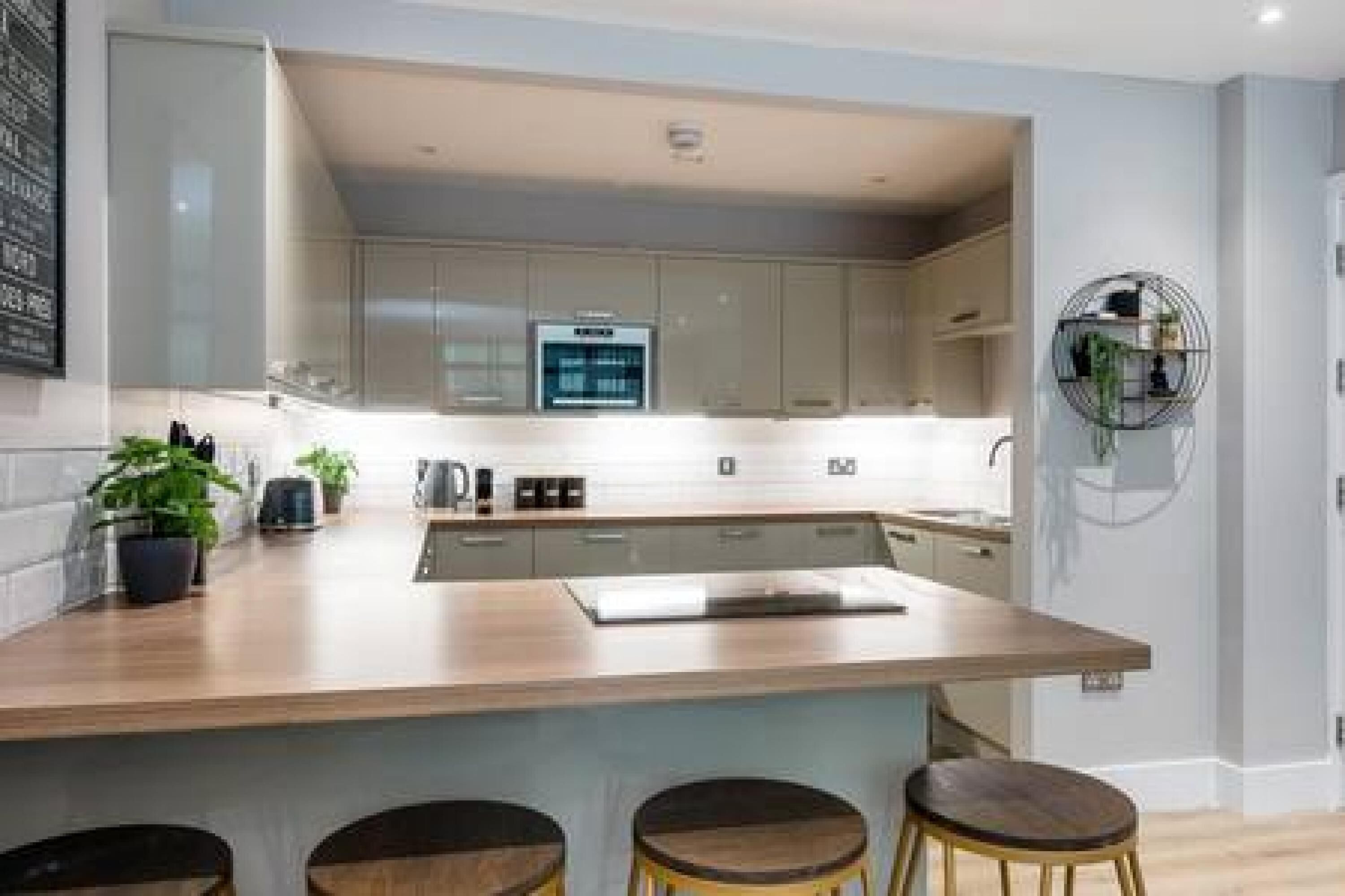 A modern kitchen with a central island, bar stools, and a built-in oven.