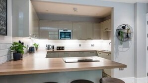 A modern kitchen with a central island, bar stools, and a built-in oven. - Host Stay Henry Street Chambers (Liverpool)