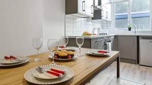 A modern kitchen with white cabinets, a wooden countertop, and a window with blinds. - Host Stay Slater Street Apartments (Liverpool)