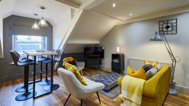 Een modern loft appartement met een eethoek, zitplaatsen, een televisie en een radiator.
