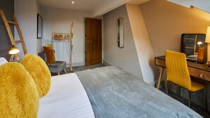 Een moderne hotelkamer met een bed, een bureau, een stoel, een spiegel en een deur.