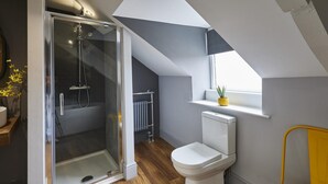 Een moderne badkamer met een douchecabine van glas, een wit toilet en een gele stoel.